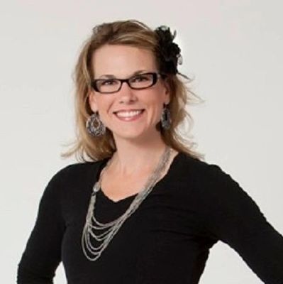 Smiling woman with glasses and jewelry.