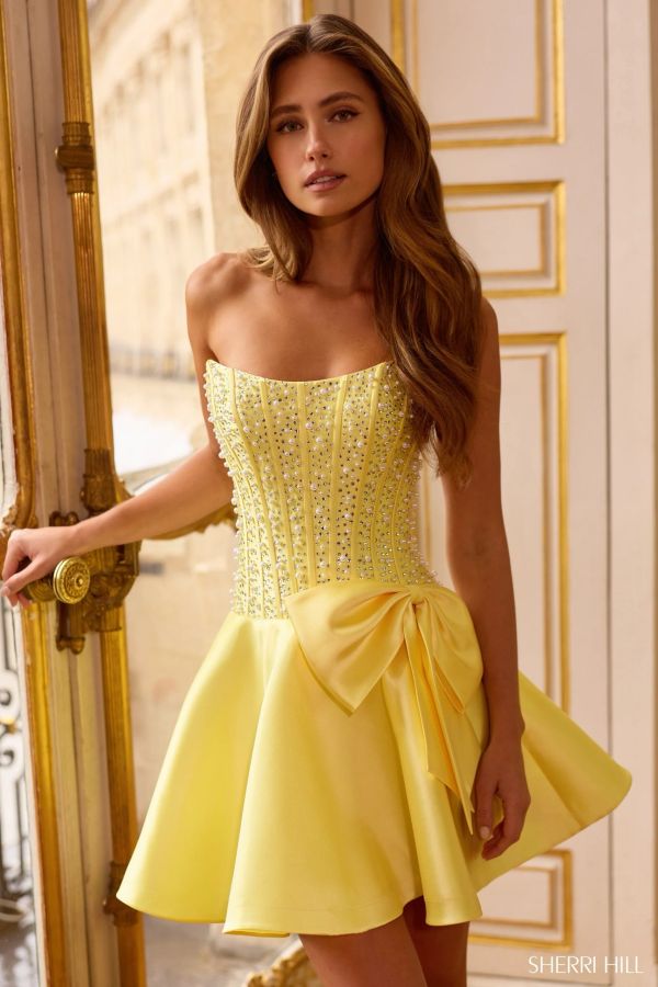 Elegant woman in a yellow embellished dress with a large bow.