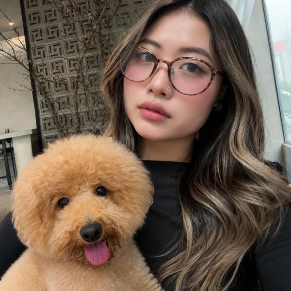 Woman with glasses holding a fluffy dog.