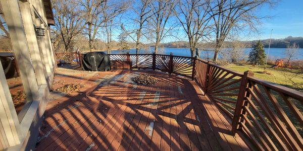 Sunny lakeside wooden deck with bare trees in fall.