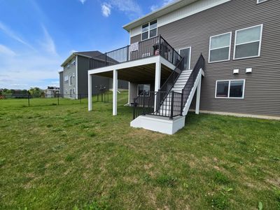 Backyard view of a house with a raised deck and stairs.