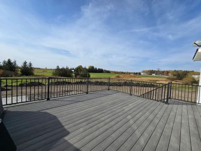 Spacious deck overlooking farmland under a blue sky.