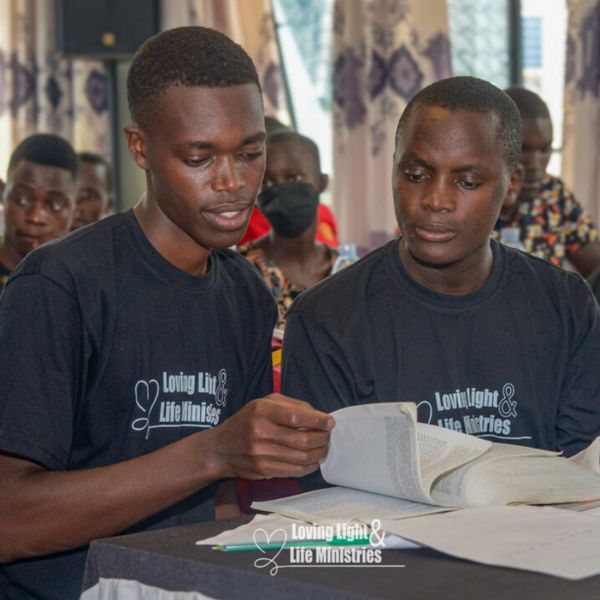 Two young men studying together at a Loving Light &amp; Life Ministries event.