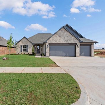 Modern single-story house with a three-car garage and a well-kept lawn.