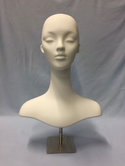 Minimalist white mannequin head and neck on a metal stand against a plain backdrop.