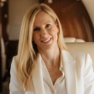 Blonde woman smiling in a white blazer.