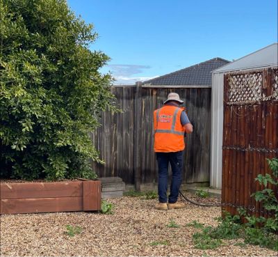 Man in orange vest gardening outdoors.