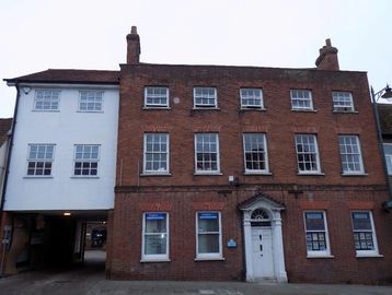 Historic brick building with white adjoining structure and multiple windows.