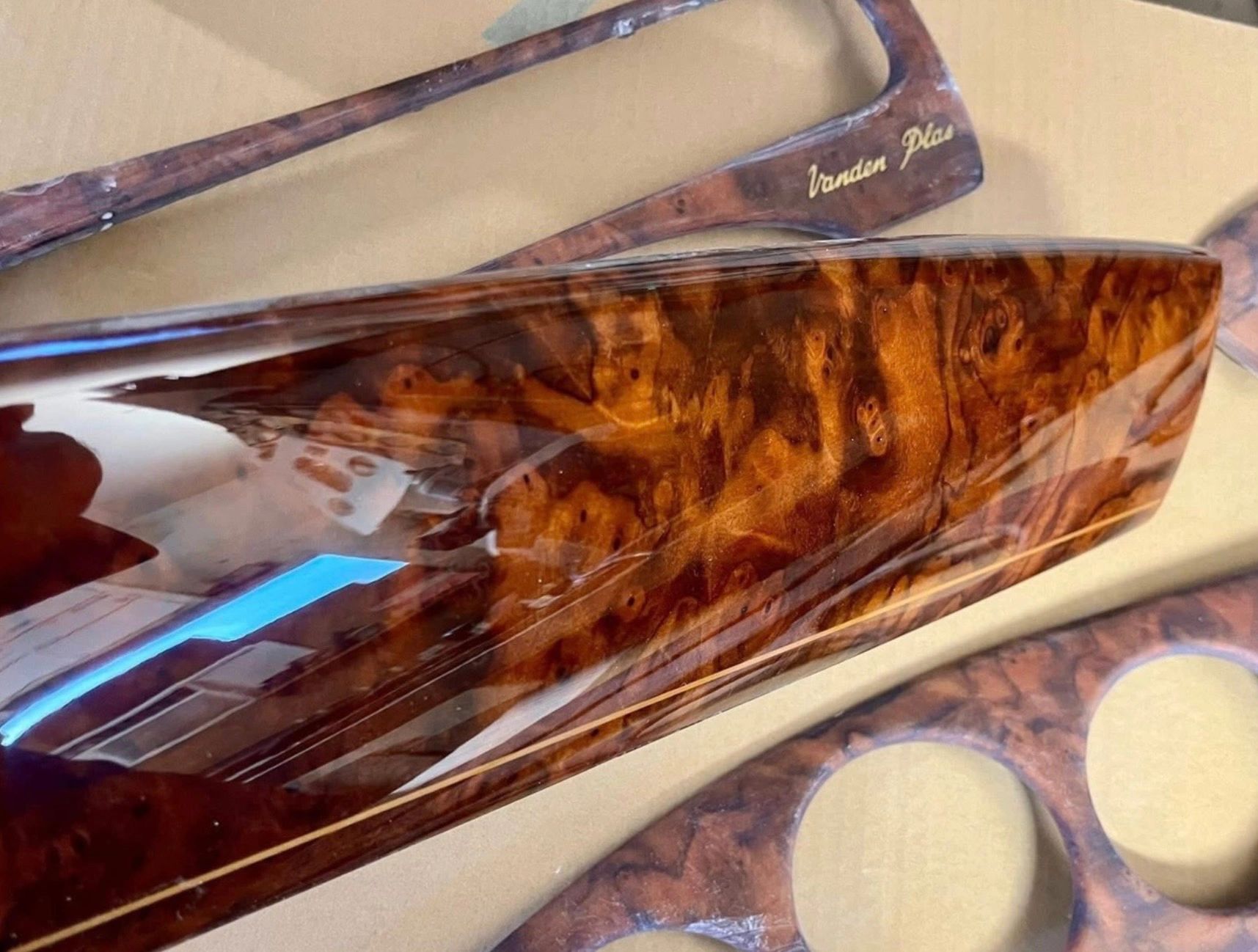 Close-up of glossy wood grain panels with intricate patterns and a piece labeled "Vanden Plas."