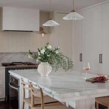 Modern kitchen with marble island and flower vase.