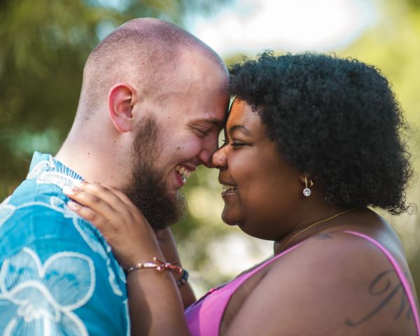Couple sharing a tender moment, smiling with foreheads touching.