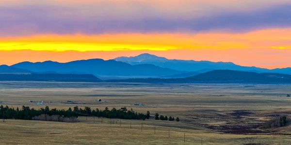 Sunset over a vast plain with mountains in the distance.
