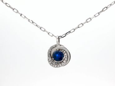 Silver necklace with a blue gemstone and diamond accents pendant.