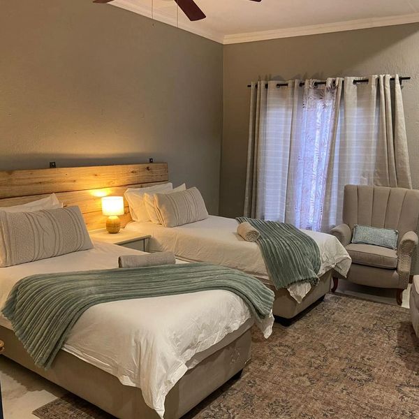 Cozy bedroom with two beds and a beige armchair.