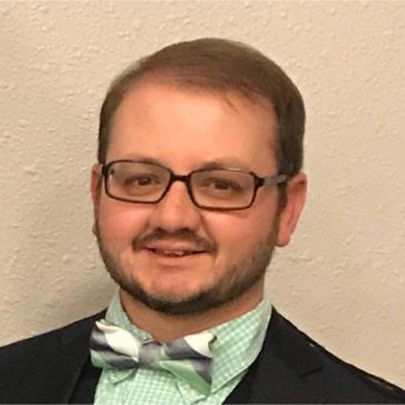Man with glasses and bow tie smiling.