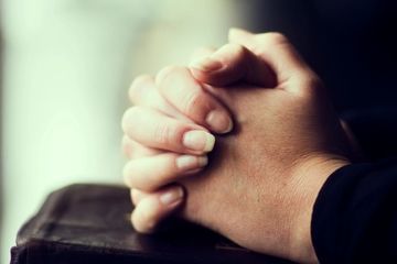 Close-up of hands clasped in prayer or contemplation.
