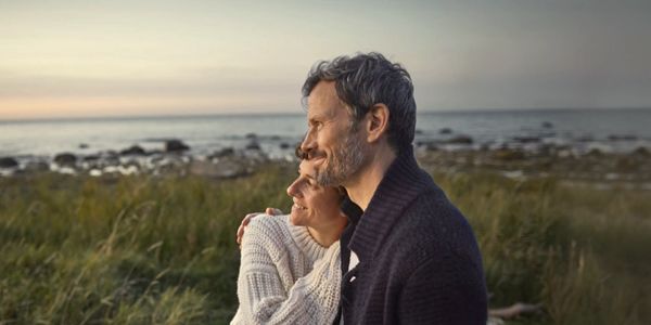 Couple embracing and enjoying a serene coastal sunset together.