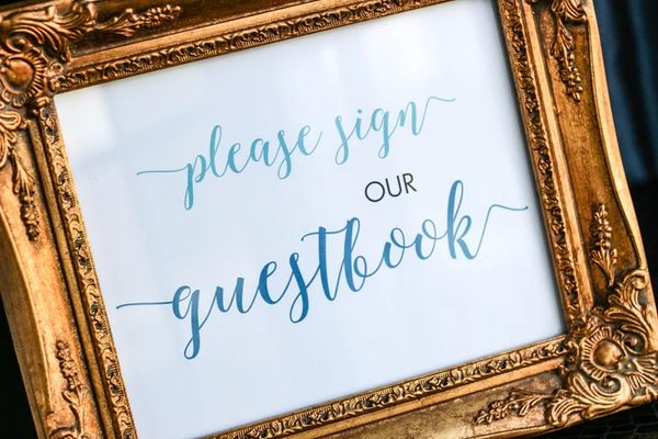 Ornate gold frame with a sign asking guests to sign a guestbook.
