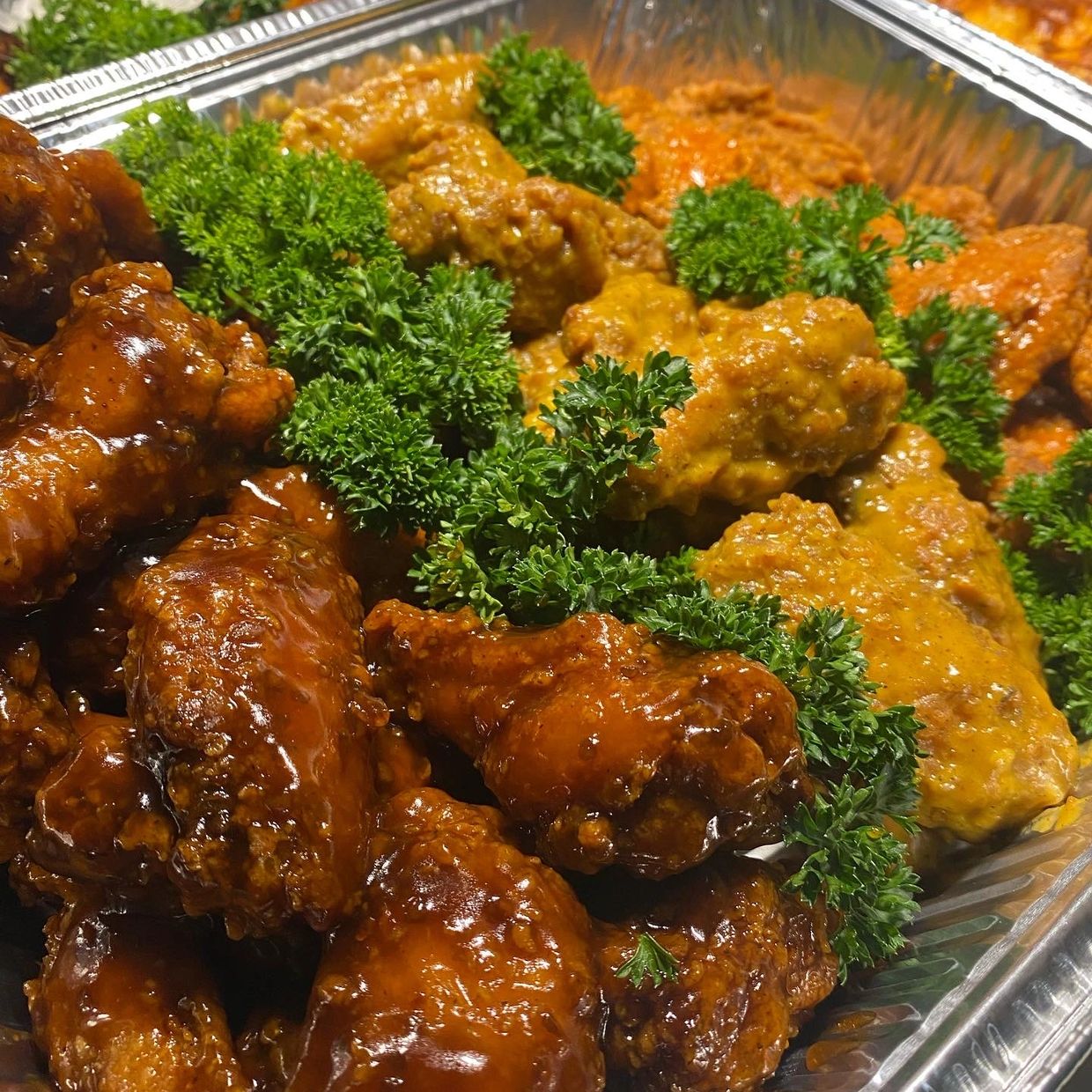 Tray of assorted saucy chicken wings garnished with parsley.