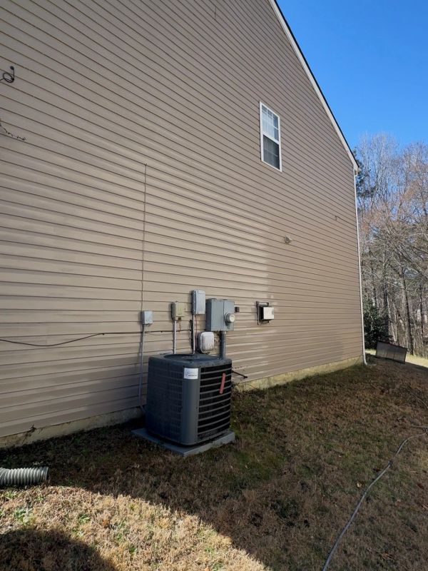 Side of a beige house with an air conditioning unit and electrical meters.