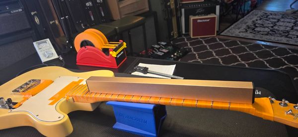 Guitar neck setup with tools for straightness check.