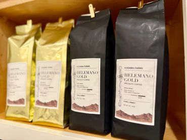 Packages of Hellemano Gold coffee on a wooden shelf.