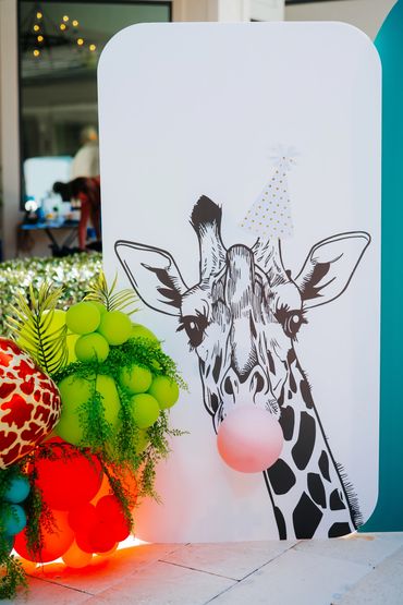 Custom giraffe backdrop with colorful balloon accents for a first birthday celebration.