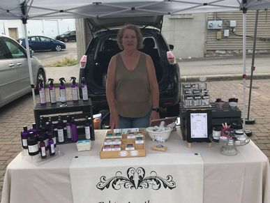Woman standing at a market stall selling products.