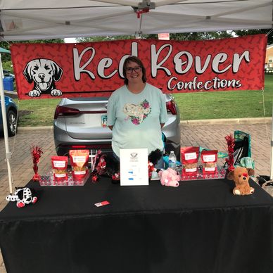 Woman at a Red Rover Confections booth with dog-themed decor.