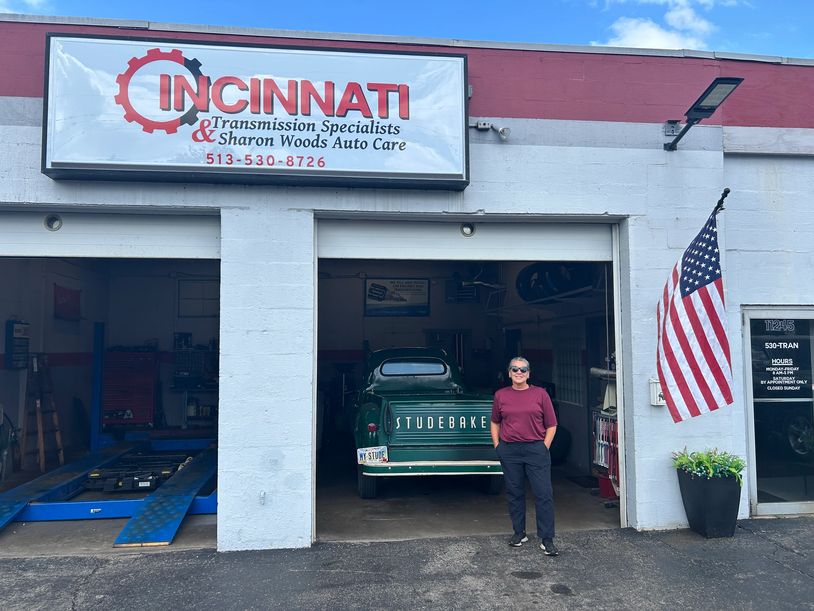 Woman standing in front of a vintage Studebaker at auto care shop.
