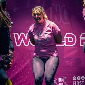 Woman in pink shirt on stage smiling.