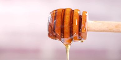 Honey dripping from a wooden honey dipper.
