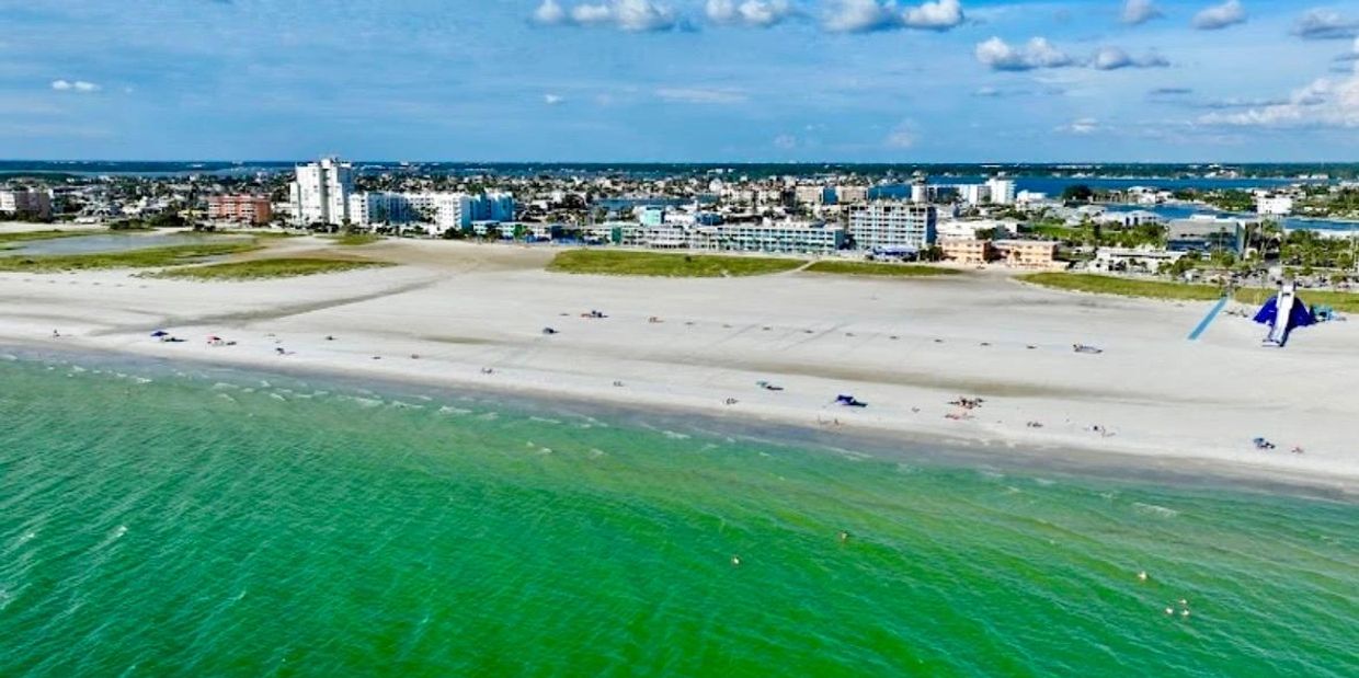 Aerial view of a beach with green water and city buildings.