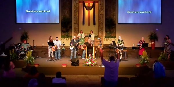 Church worship band performing with congregation raising hands.