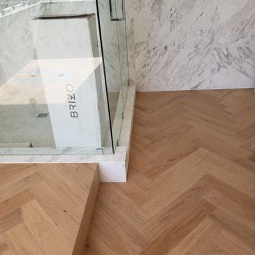 Large tiled shower walls for a sleek design, complemented by elegant wood flooring