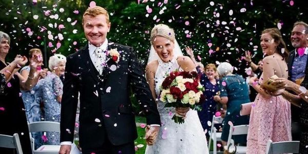 Confetti being thrown as happily married couple walk down the aisle.