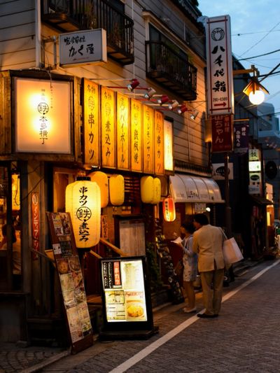 Busy Japanese street with illuminated signs at dusk.