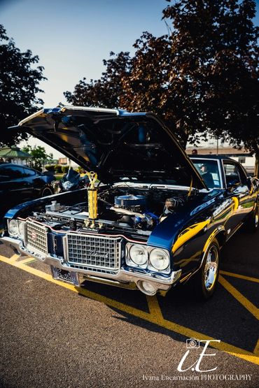 Classic black vintage car with open hood at a car show.