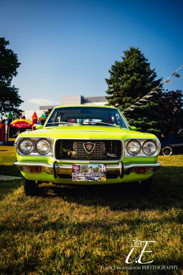Front view of a bright green vintage car on grass.