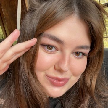 Young woman smiling with hand near forehead.