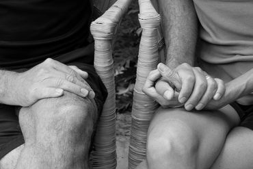 Two people holding hands while sitting side by side.