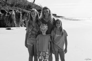 A woman with three children standing on a beach in black and white.