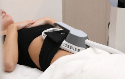 A person receiving a non-invasive body contouring treatment on the abdomen.