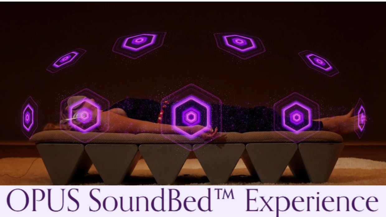 Person lying on OPUS SoundBed with purple sound waves.