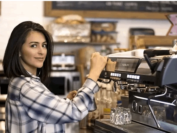 A woman in front of a coffee machine