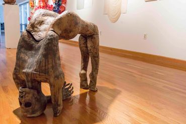 Wooden sculpture of a figure in a backbend pose.