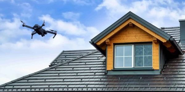 Drone flying near a house roof on a clear day.