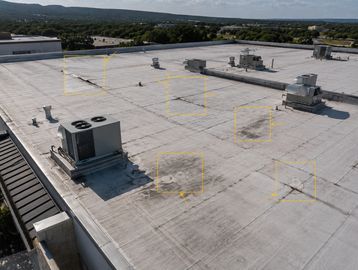 Flat commercial rooftop with HVAC units and ventilation systems under a cloudy sky.