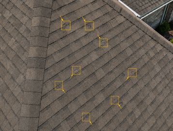 Roof with several shingles marked for inspection or damage.
