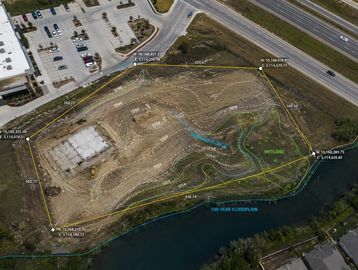 Aerial view of a construction site with marked boundaries and floodplain areas.